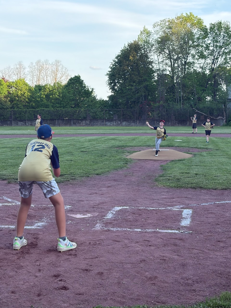 Youth Baseball scene with pitcher throwing and catcher waiting