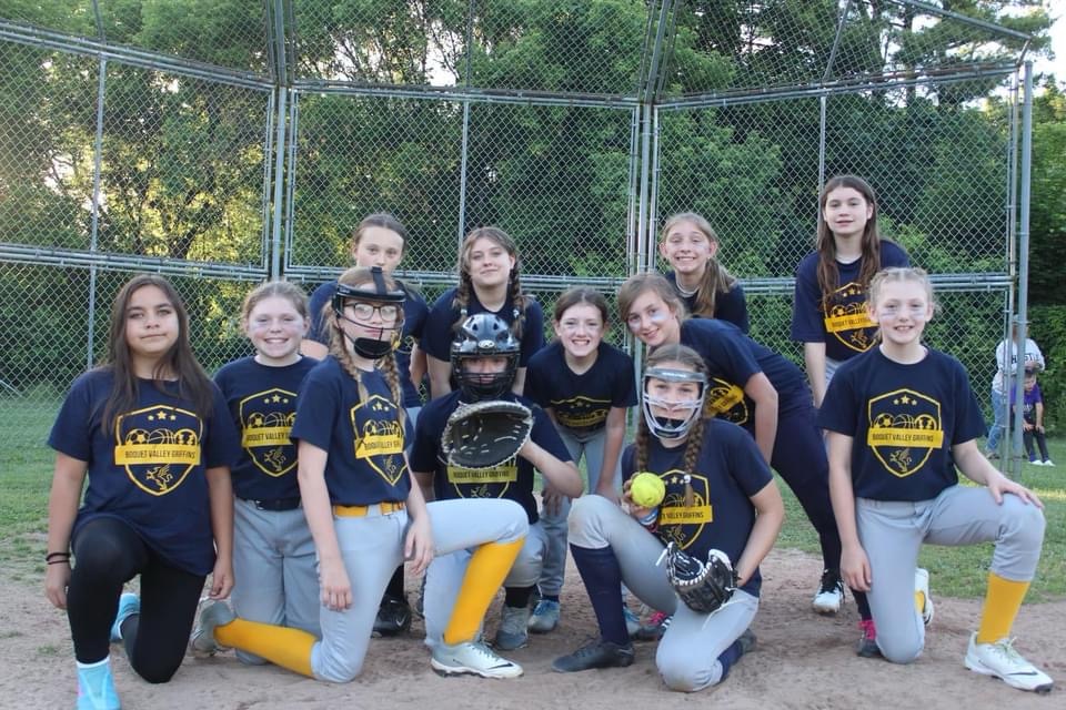 Softball team posing in front of backstop