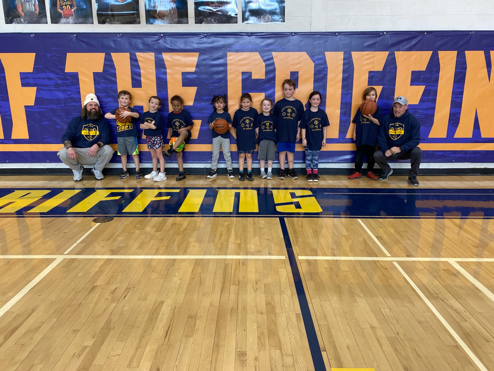 Young kids team posing with coaches on basketball court