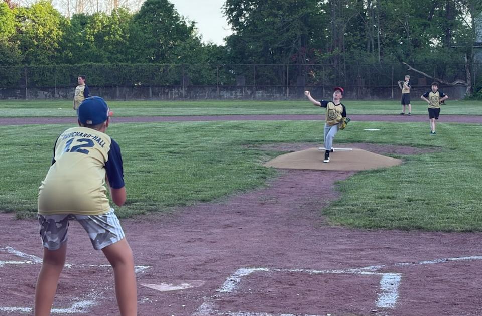 Youth Baseball scene with pitcher throwing and catcher waiting