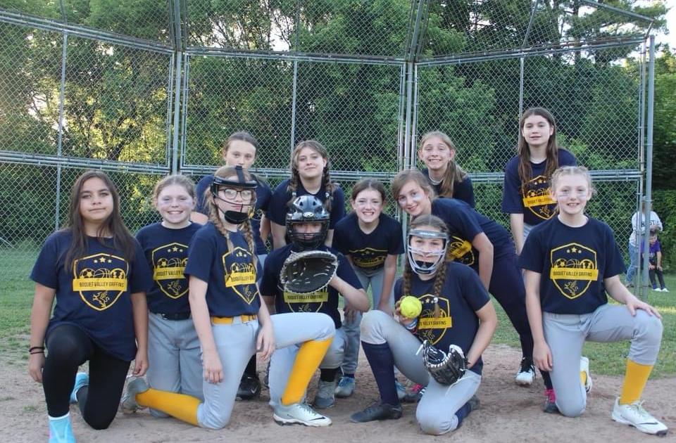 Softball team posing in front of backstop