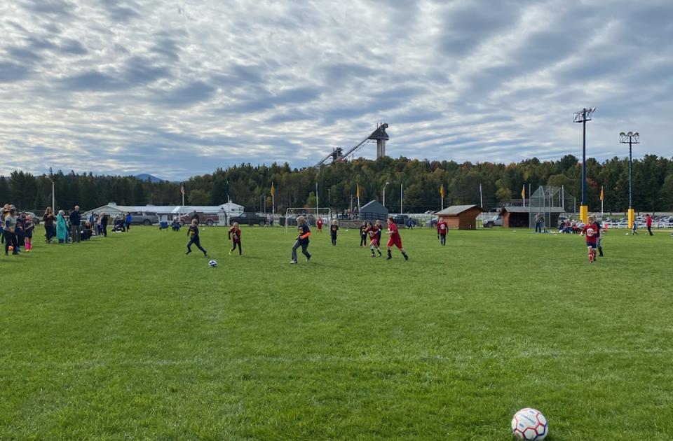 Children playing soccer with the Olympic ski jumps in the background