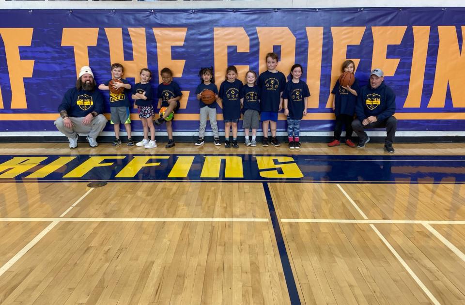 Young kids team posing with coaches on basketball court