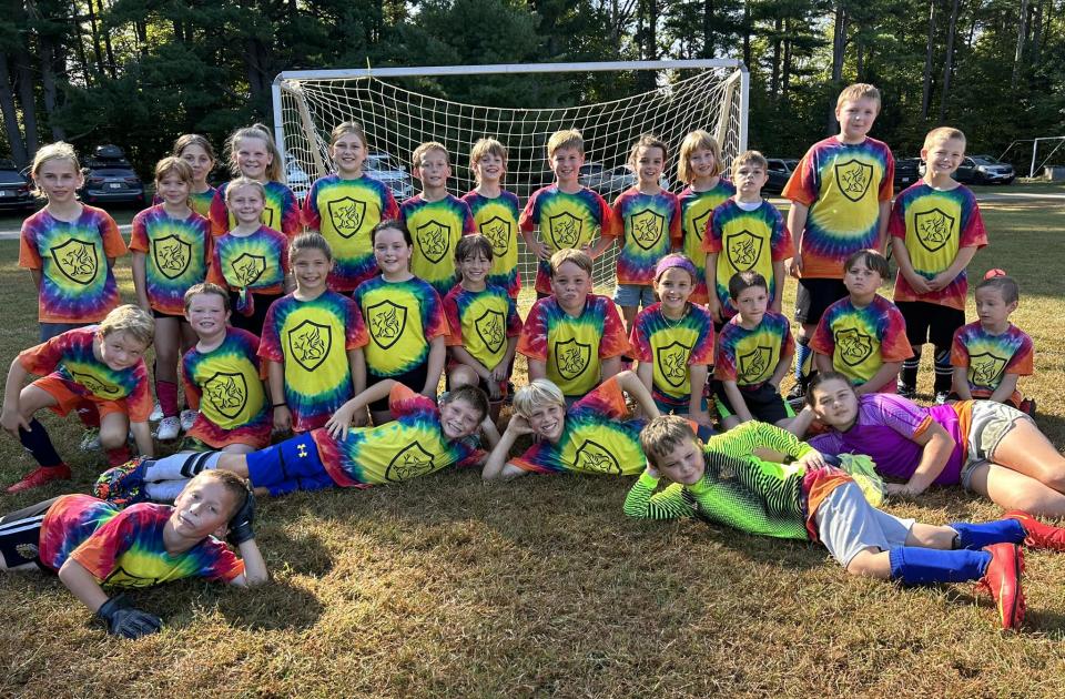 Soccer team in tie-dye posing together with their coaches